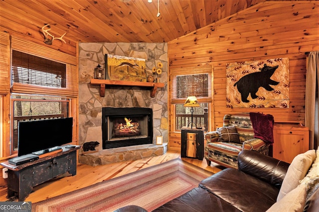 living area with a fireplace, wooden walls, wood finished floors, high vaulted ceiling, and wooden ceiling