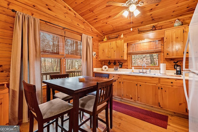 kitchen with lofted ceiling, wood walls, a sink, light countertops, and freestanding refrigerator