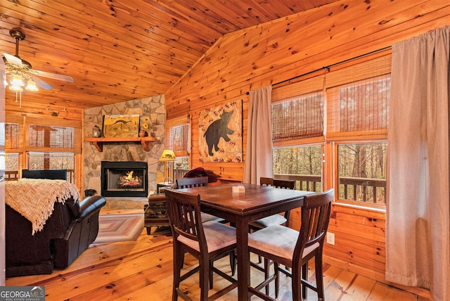 dining space featuring lofted ceiling, wooden ceiling, wood-type flooring, wood walls, and a fireplace