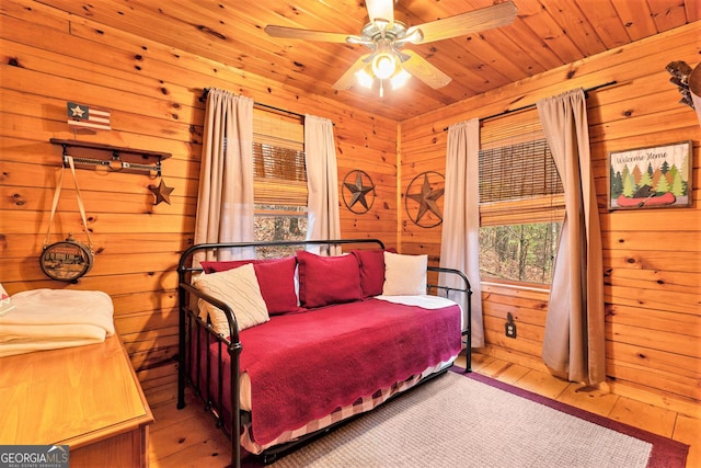 bedroom featuring a ceiling fan, wood ceiling, wooden walls, and hardwood / wood-style flooring