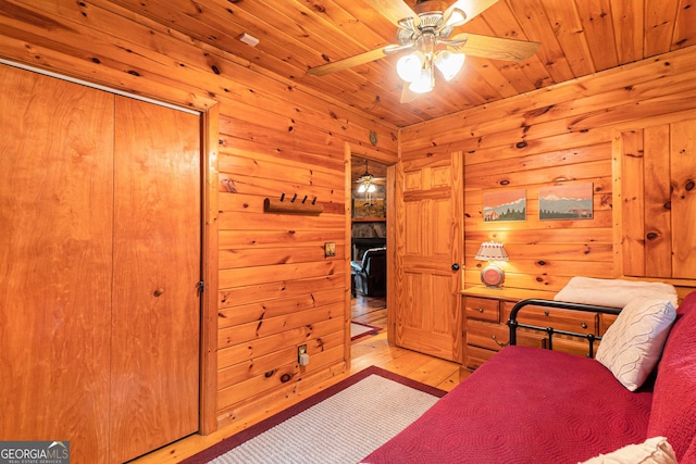 bedroom with wood ceiling, wood walls, light wood-style flooring, and ceiling fan