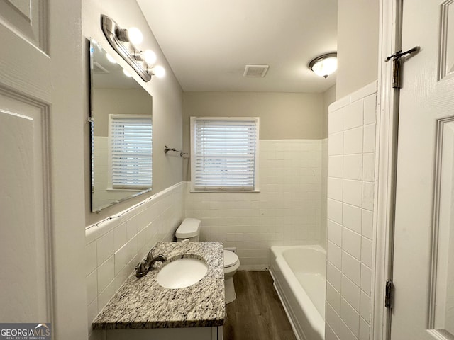 bathroom featuring vanity, toilet, wood-type flooring, and tile walls