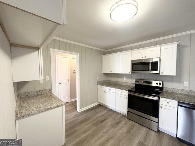 kitchen with crown molding, appliances with stainless steel finishes, light stone countertops, light hardwood / wood-style floors, and white cabinets