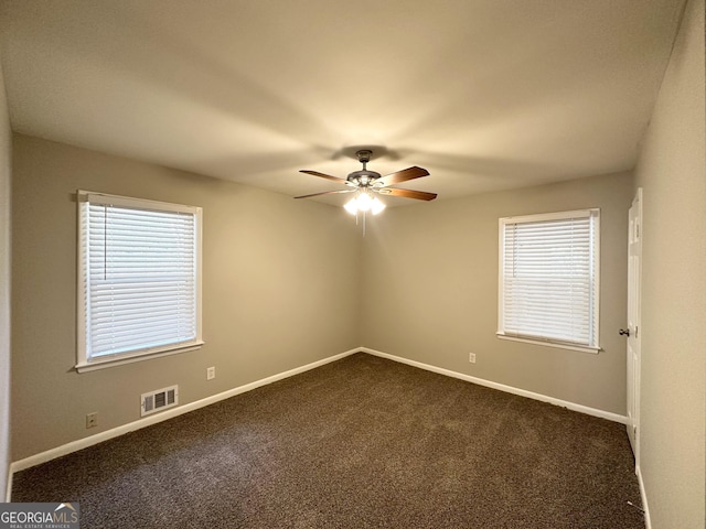 empty room with ceiling fan and dark carpet