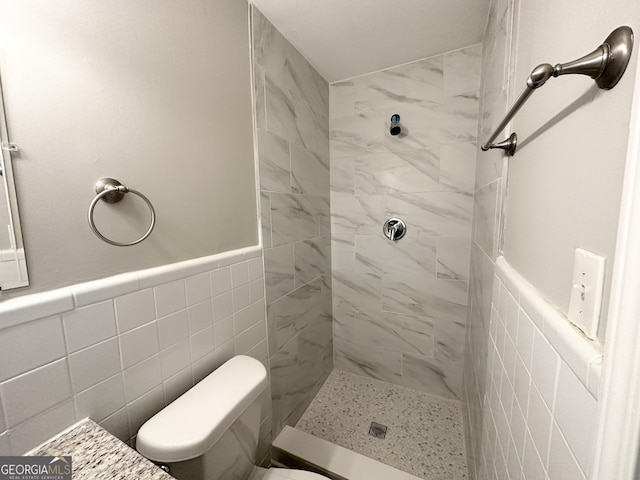 bathroom with tiled shower, toilet, and tile walls