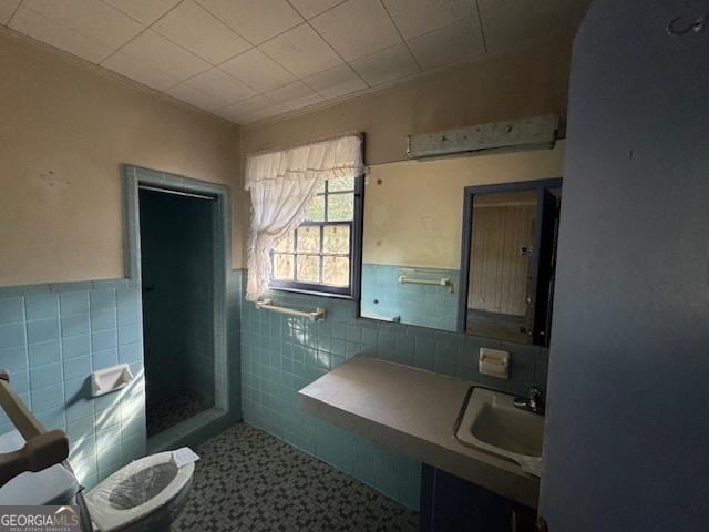 bathroom with walk in shower, toilet, sink, tile walls, and tile patterned flooring