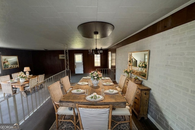 dining room featuring a chandelier and brick wall