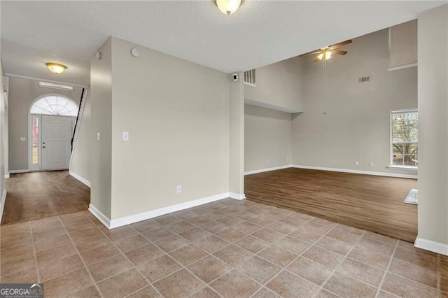 empty room featuring hardwood / wood-style floors, a textured ceiling, ceiling fan, and a high ceiling