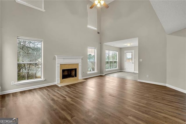 unfurnished living room featuring dark hardwood / wood-style floors, ceiling fan, a premium fireplace, and high vaulted ceiling