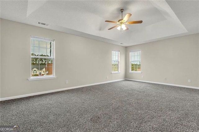 carpeted empty room featuring a textured ceiling, a raised ceiling, and ceiling fan