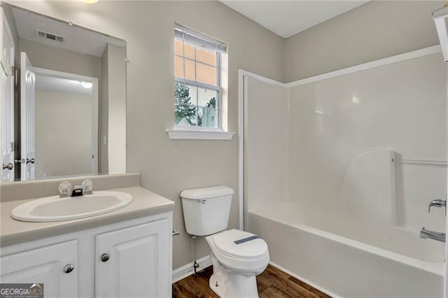 full bathroom with vanity, hardwood / wood-style flooring, shower / tub combination, and toilet