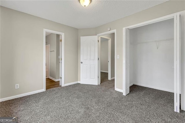 unfurnished bedroom with dark carpet, a closet, and a textured ceiling