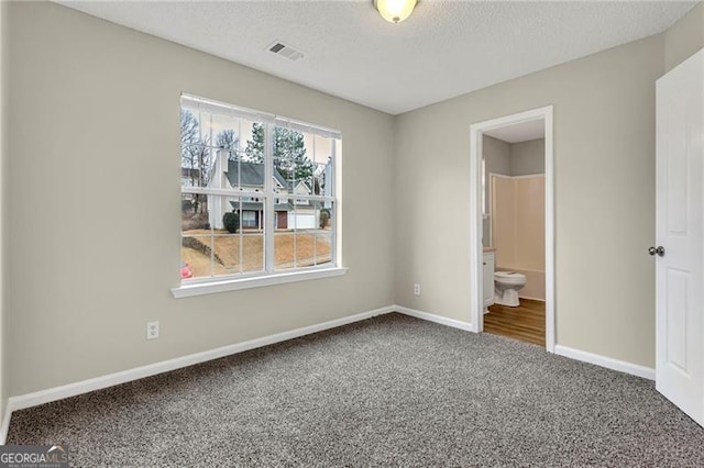 unfurnished bedroom featuring connected bathroom, carpet floors, and a textured ceiling