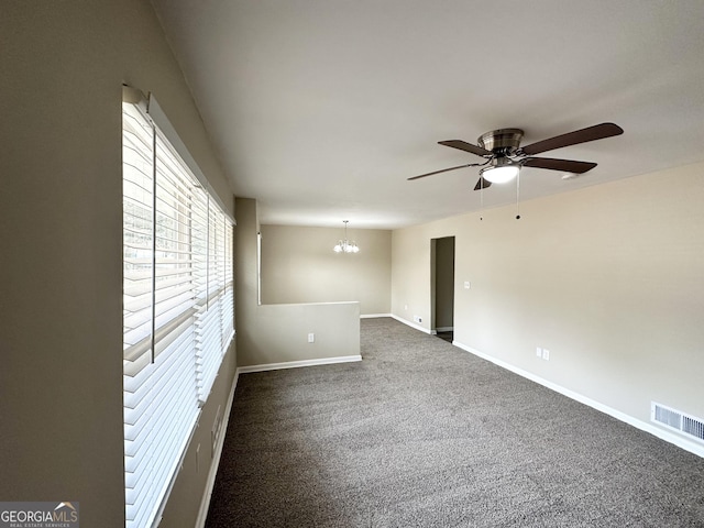 carpeted spare room featuring ceiling fan with notable chandelier