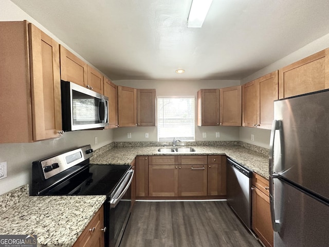 kitchen with sink, light stone countertops, dark hardwood / wood-style floors, and appliances with stainless steel finishes