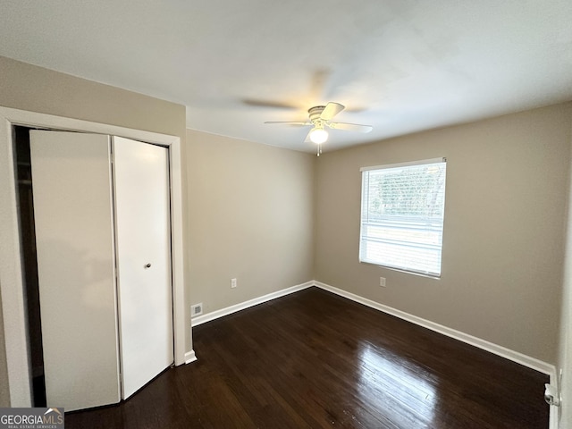 unfurnished bedroom with ceiling fan, dark hardwood / wood-style floors, and a closet