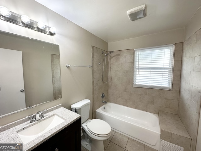 full bathroom featuring tile patterned flooring, vanity, tiled shower / bath combo, and toilet