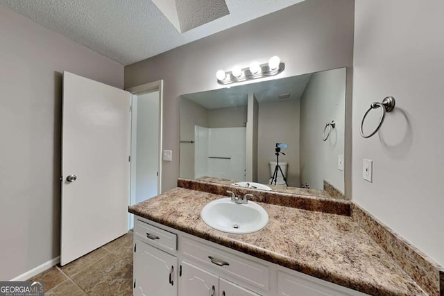 bathroom with vanity, a textured ceiling, and walk in shower