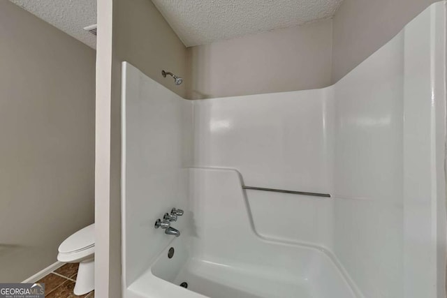 bathroom with bathtub / shower combination, tile patterned floors, toilet, and a textured ceiling