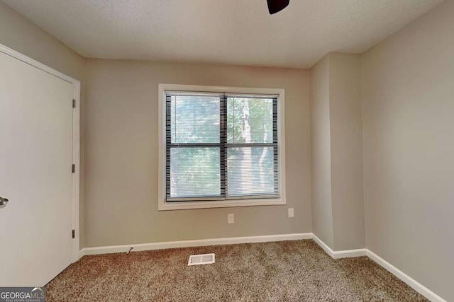 unfurnished room with light colored carpet and a textured ceiling