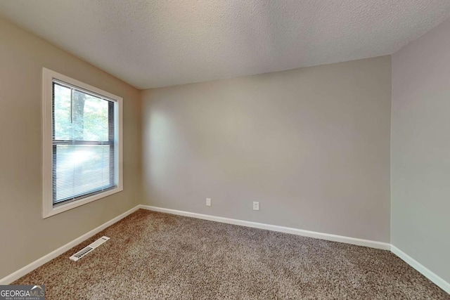 empty room with carpet floors and a textured ceiling