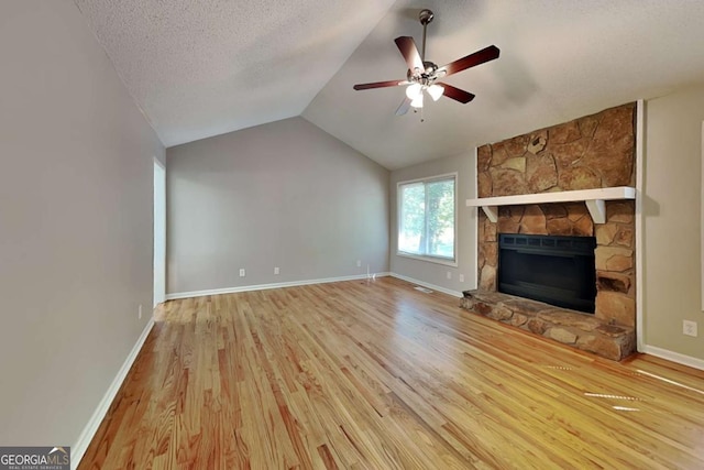 unfurnished living room with a fireplace, lofted ceiling, light wood-type flooring, ceiling fan, and a textured ceiling