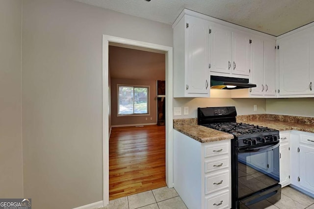 kitchen with light tile patterned flooring, white cabinetry, a textured ceiling, black range with gas stovetop, and dark stone counters