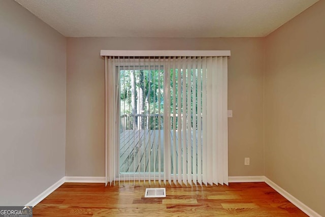 empty room with light hardwood / wood-style floors and a textured ceiling