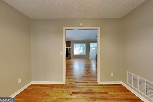 empty room featuring light hardwood / wood-style floors, a large fireplace, and a textured ceiling