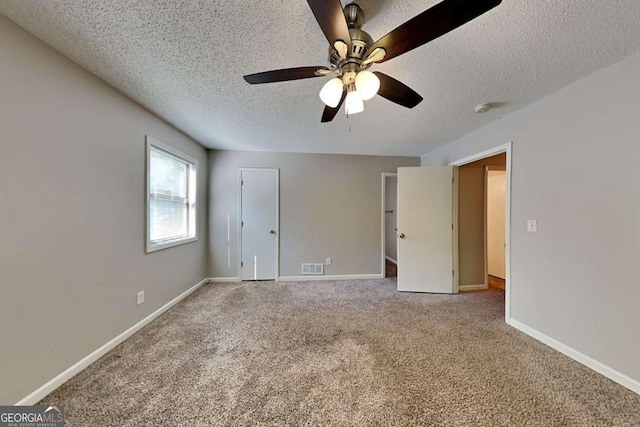 carpeted empty room with ceiling fan and a textured ceiling