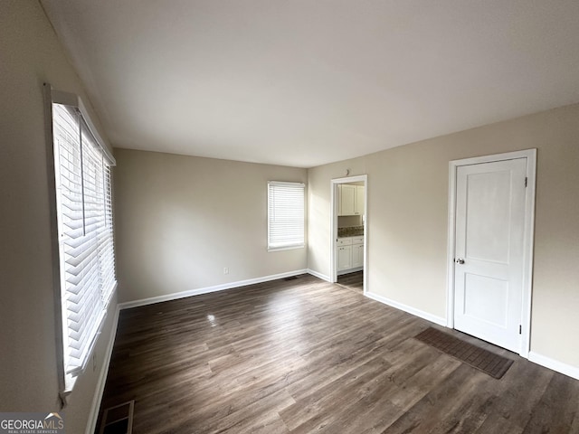 unfurnished bedroom featuring dark wood-type flooring and ensuite bathroom