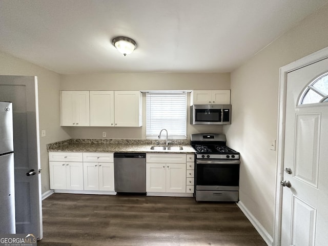 kitchen featuring sink, dark stone counters, white cabinets, and appliances with stainless steel finishes