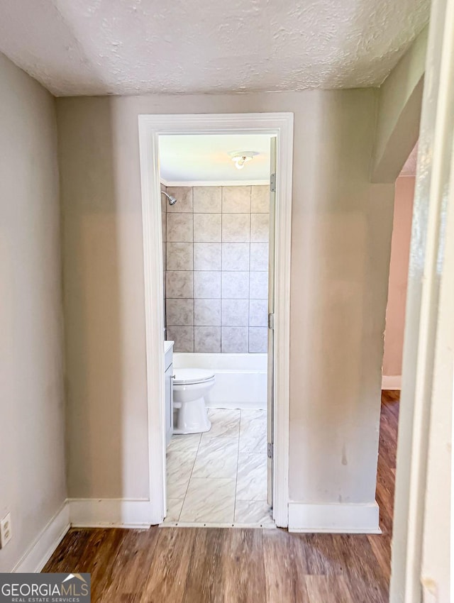 corridor with hardwood / wood-style floors and a textured ceiling