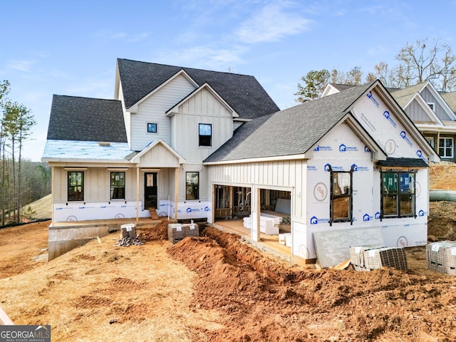 view of front facade featuring board and batten siding, roof with shingles, and a patio