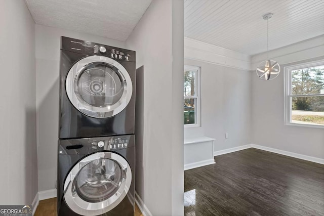 laundry room featuring a chandelier, dark hardwood / wood-style floors, a textured ceiling, and stacked washer / dryer