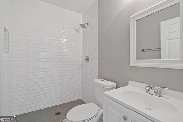 bathroom with vanity, toilet, and tiled shower