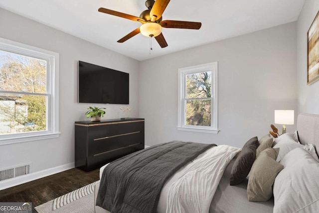 bedroom with multiple windows, dark hardwood / wood-style floors, and ceiling fan