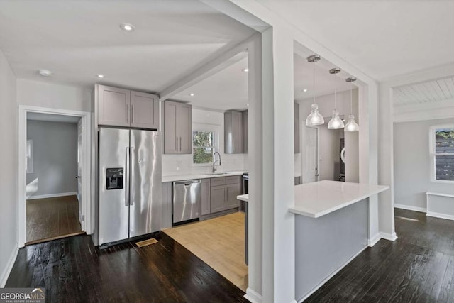 kitchen with gray cabinets, appliances with stainless steel finishes, sink, and decorative light fixtures