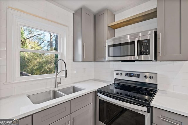 kitchen featuring gray cabinetry, sink, tasteful backsplash, and appliances with stainless steel finishes