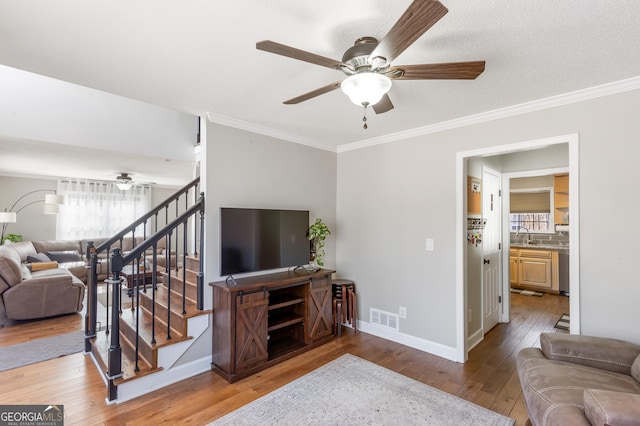 living room featuring hardwood / wood-style flooring, crown molding, sink, and ceiling fan