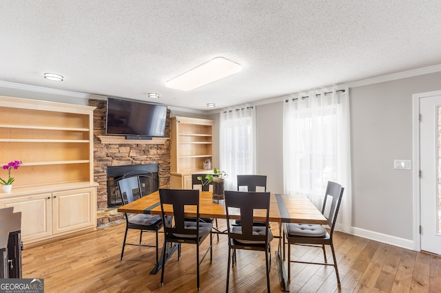 dining room with crown molding, a fireplace, a textured ceiling, and light wood-type flooring