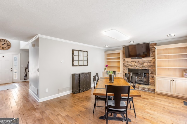 dining area featuring ornamental molding, light hardwood / wood-style floors, and a textured ceiling