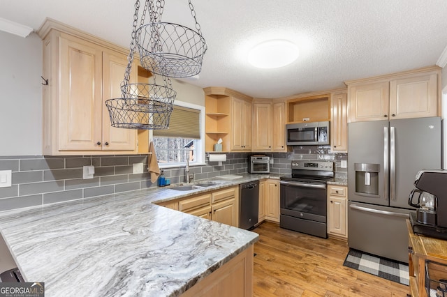 kitchen with sink, stainless steel appliances, light hardwood / wood-style floors, decorative light fixtures, and light brown cabinets