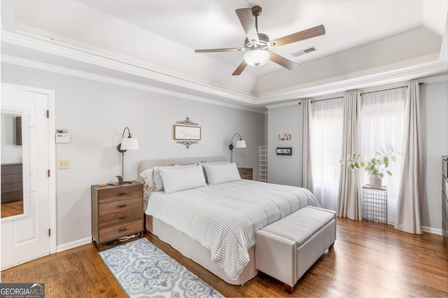 bedroom with hardwood / wood-style flooring, crown molding, a raised ceiling, and access to outside