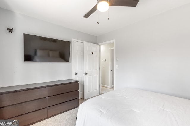 bedroom featuring light colored carpet, ceiling fan, and a closet