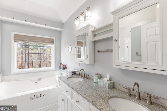 bathroom with lofted ceiling, vanity, and a bathtub