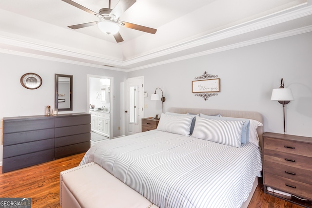 bedroom featuring crown molding, ensuite bath, a raised ceiling, hardwood / wood-style flooring, and ceiling fan