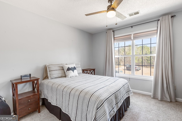 carpeted bedroom with ceiling fan and a textured ceiling