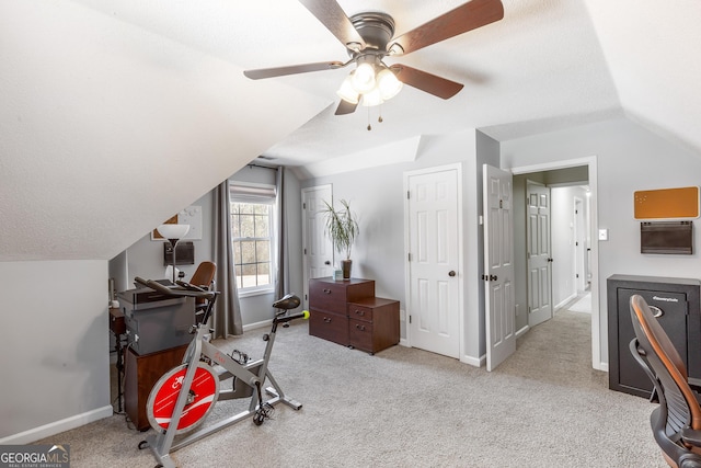 exercise room featuring light colored carpet, vaulted ceiling, and a textured ceiling