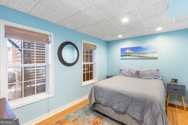 bedroom featuring wood-type flooring and a drop ceiling